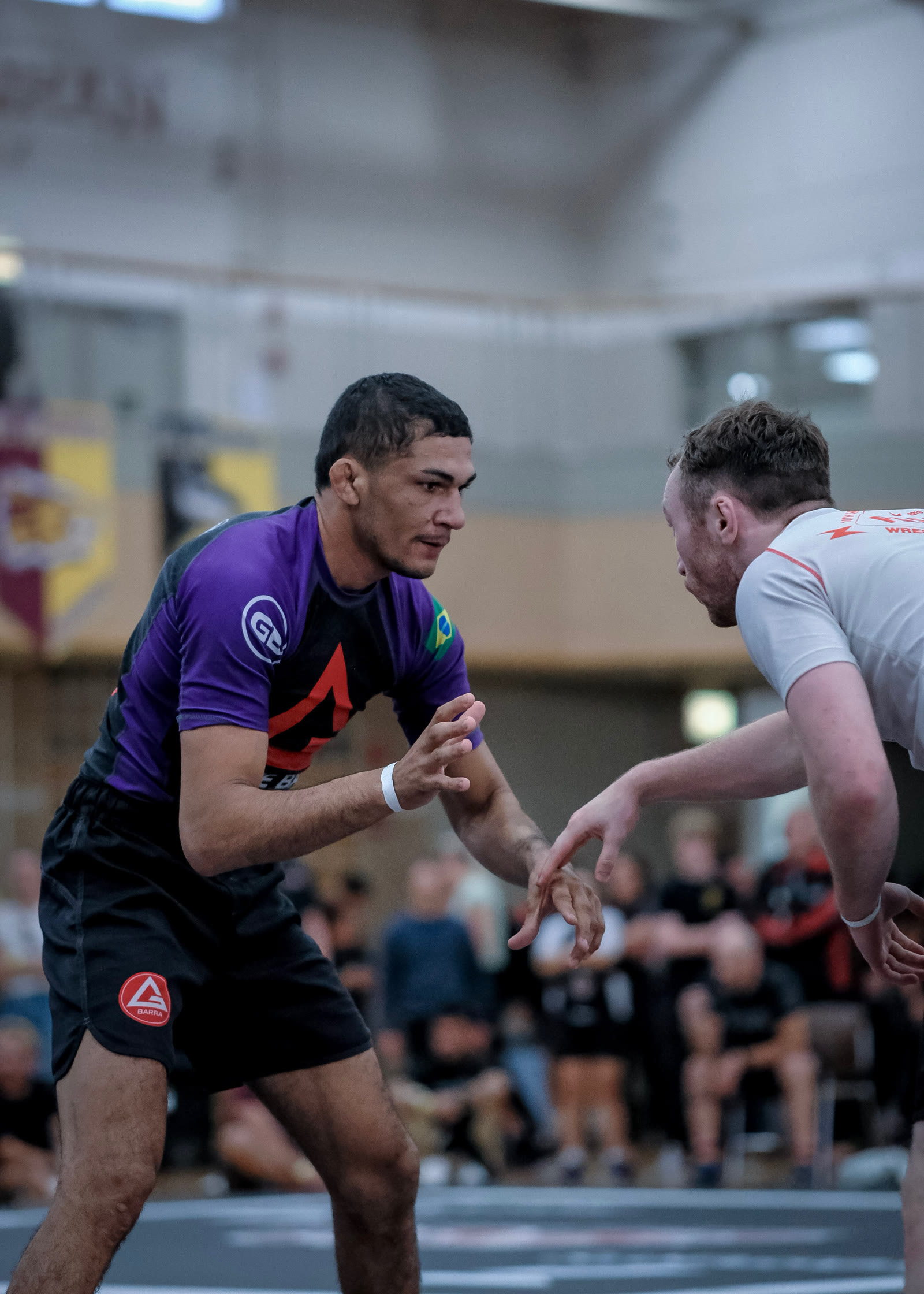 Wellington Andrade in a Gracie Barra rashguard, hands up, facing an opponent.