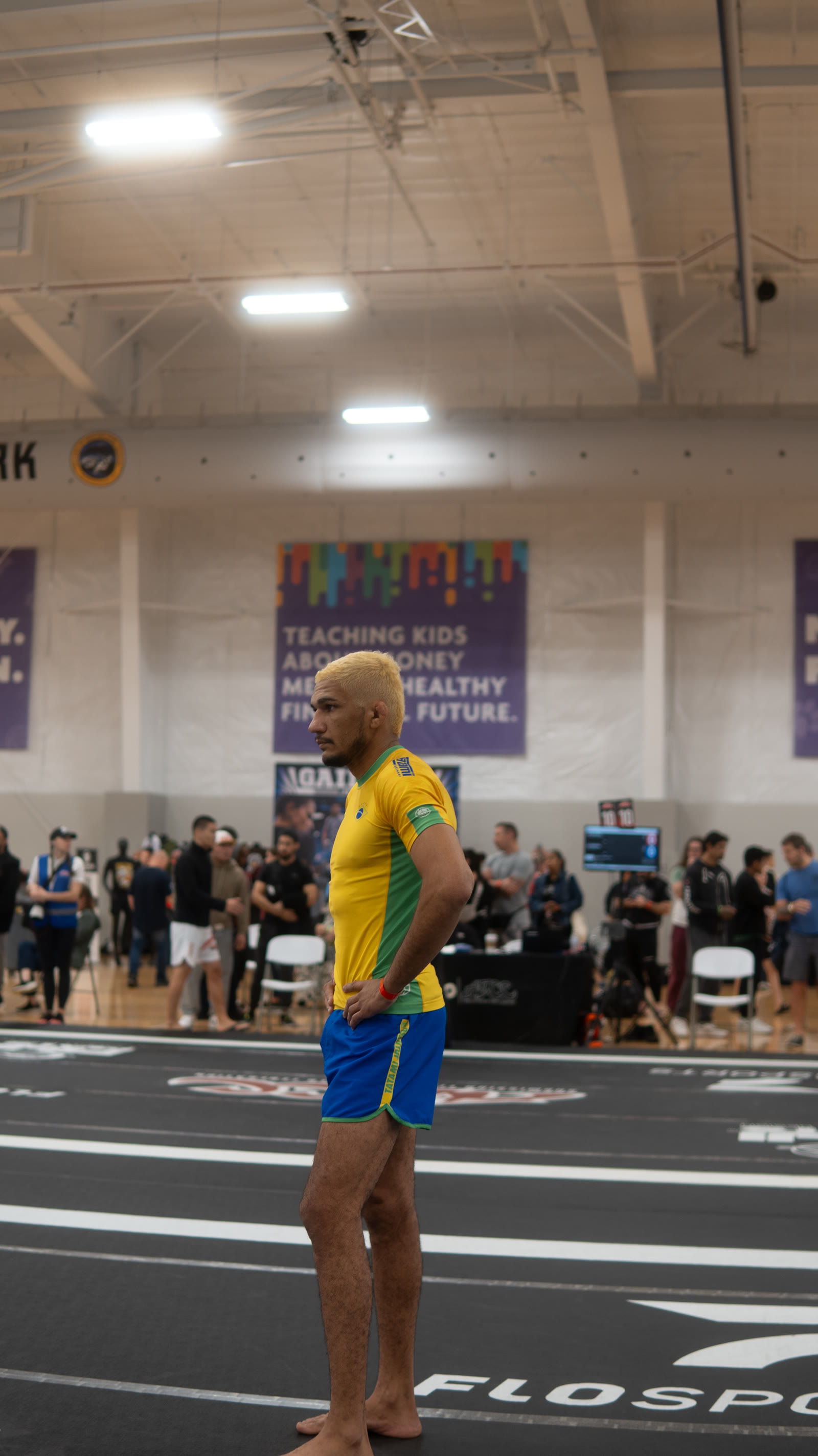 Wellington Andrade in profile, yellow and green rashguard, on a competition mat.